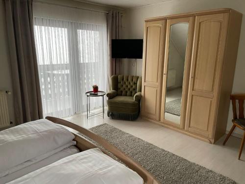 a room with a bedroom with a mirror and a chair at Gasthaus Hubertus in Reuth