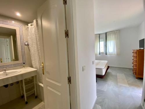 a bathroom with a sink and a mirror and a bed at Entre hoyos y la playa Grupo AC Gestion in Novo Sancti Petri