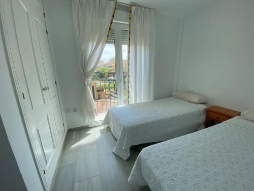 a bedroom with two beds and a large window at Entre hoyos y la playa Grupo AC Gestion in Novo Sancti Petri