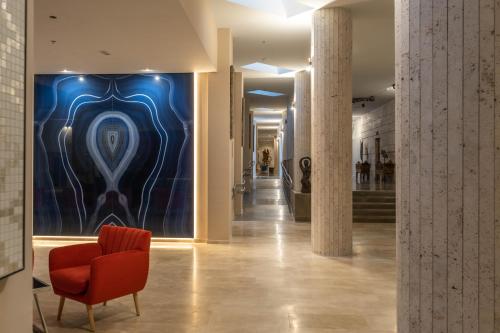 a hallway with a red chair and a blue wall at Cádiz Bahía by QHotels in Cádiz