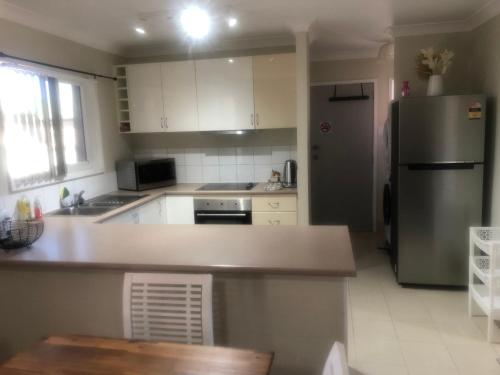 a kitchen with white cabinets and a stainless steel refrigerator at Branxton Baybrook Apartment in Branxton