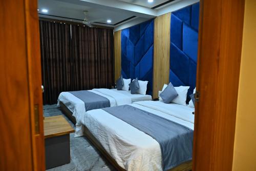 two beds in a room with a blue wall at HOTEL SURY VILLA in Ahmedabad