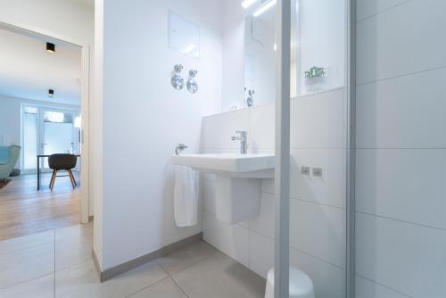een witte badkamer met een wastafel en een douche bij KellenHus Wohnung 3 in Kellenhusen