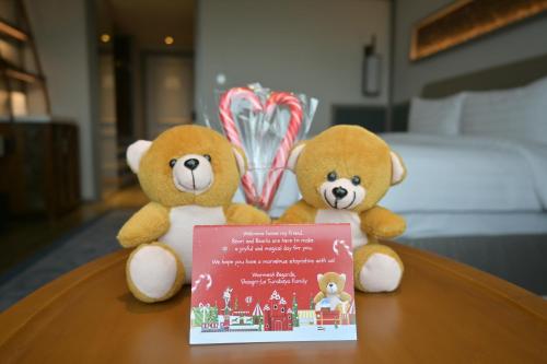 two teddy bears sitting on a table with a book at Shangri-la Surabaya in Surabaya