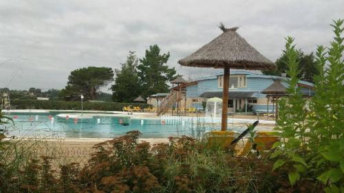 une piscine avec un parasol et un bâtiment dans l'établissement APPARTEMENT DE 24 M2 à BARBOTAN-Minimum 21 nuits-CLIMATISé #VACANCES#CURE--lac et piscine à 1 km, à Cazaubon
