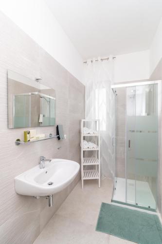 a white bathroom with a sink and a shower at Pietra Fiorita Dimora in Conversano