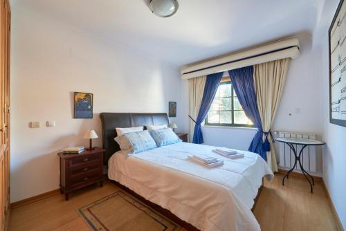 um quarto com uma cama com cortinas azuis e uma janela em Apartamento junto NOVA&PRAIA Carcavelos II em Carcavelos