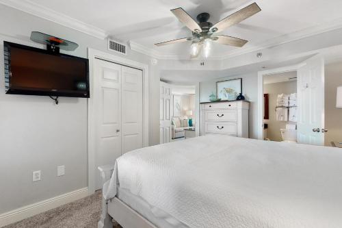 a white bedroom with a bed and a ceiling fan at Phoenix Vll 1002 in Orange Beach