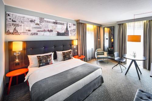 Cette chambre comprend un grand lit et un bureau. dans l'établissement Holiday Inn Lübeck, an IHG Hotel, à Lübeck