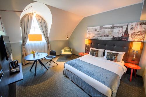a hotel room with a large bed and a table at Holiday Inn Lübeck by IHG in Lübeck