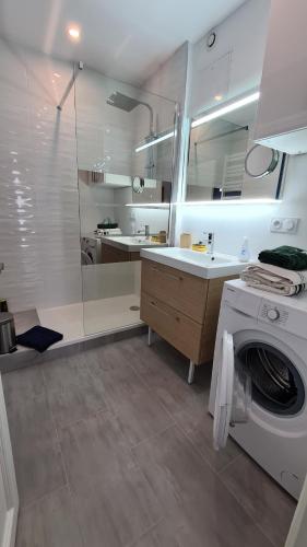 une salle de bain avec une machine à laver et un lavabo dans l'établissement Superbe appartement climatisé, 2 chambres à 200m de la plage, au Grau-du-Roi
