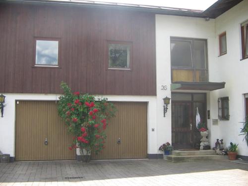 a building with two garage doors and a plant with red flowers at Appartement im Souterrain mit Terrasse in Bischofswiesen