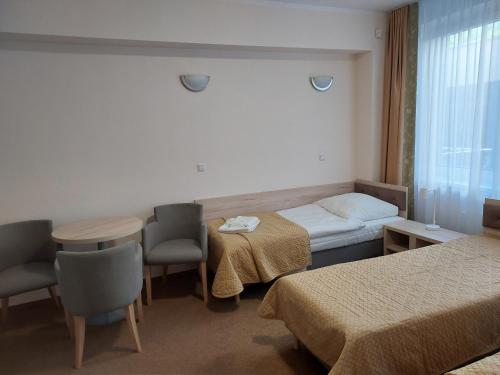 ein Hotelzimmer mit 2 Betten, einem Tisch und Stühlen in der Unterkunft Sasanka in Świnoujście