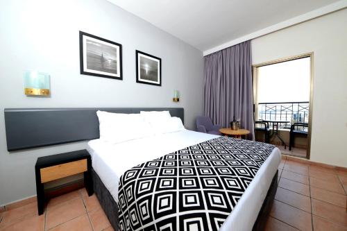 um quarto de hotel com uma cama e uma varanda em Comfort Hotel Eilat em Eilat