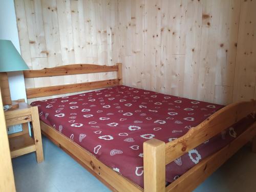 un lit dans une chambre avec un mur en bois dans l'établissement Appartement 4 pers Termignon avec wifi, parking, casier à ski - FR-1-508-151, à Termignon