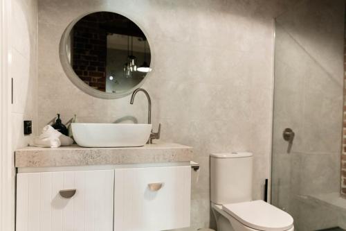 a bathroom with a sink and a toilet and a mirror at Oxford on Otho in Inverell