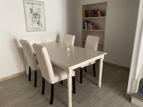 uma mesa de jantar branca com cadeiras brancas e uma estante de livros em La Maison de Chablis em Chablis