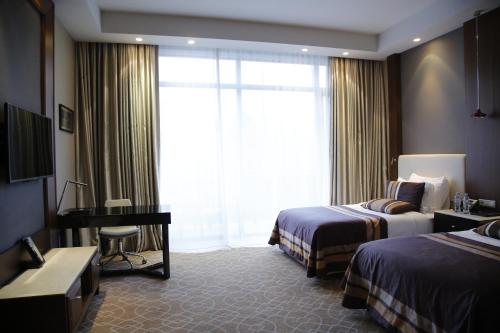 a hotel room with two beds and a desk and a window at Borjomi Likani Health & Spa Centre in Borjomi