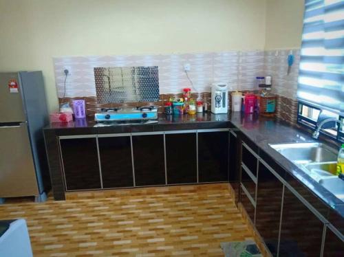 a kitchen with a counter with a sink and a refrigerator at Zarina's Budget Homestay in Tumpat