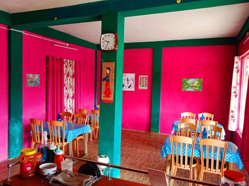ein Esszimmer mit rosa Wänden sowie einem Tisch und Stühlen in der Unterkunft Well Spring Homestay in Kalimpong