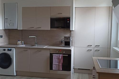 a kitchen with white cabinets and a sink and a dishwasher at Suresnes : 2 pièces cosy in Suresnes