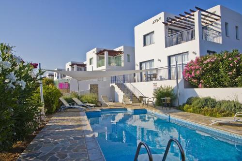 a villa with a swimming pool in front of a house at Meltemi Villas in Paphos City