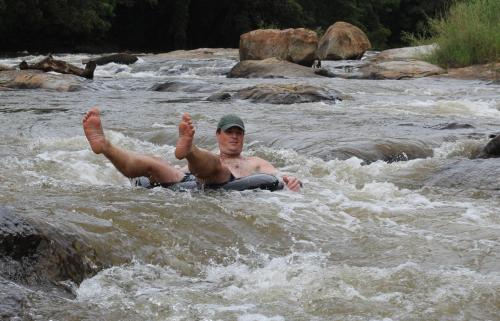 a man laying in the water in a river at Lions Rock Rapids - Luxury Tented Camp in Hazyview