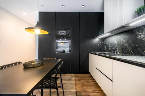 a black and white kitchen with a table and a counter at Botanical Garden loft in Kaunas