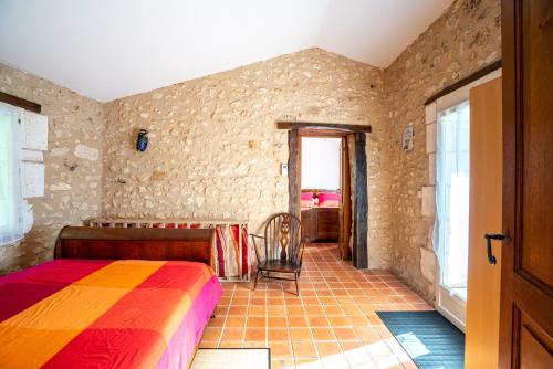 ein Schlafzimmer mit einem Bett mit einer bunten Decke in der Unterkunft Gîte de La Vieille Bécane in La Gonterie-Boulouneix