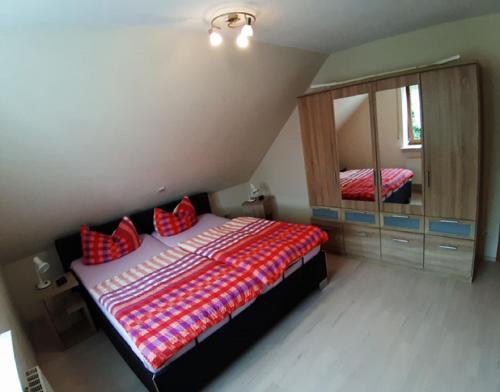Schlafzimmer mit einem Bett mit roten Kissen und einem Spiegel in der Unterkunft Ferienwohnung Reuter Christine in Bad Staffelstein
