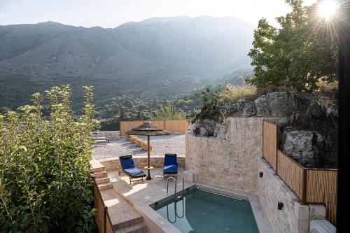 a swimming pool with two chairs and a view of a mountain at Luxury love nest with hot tub & heated pool in Kournás