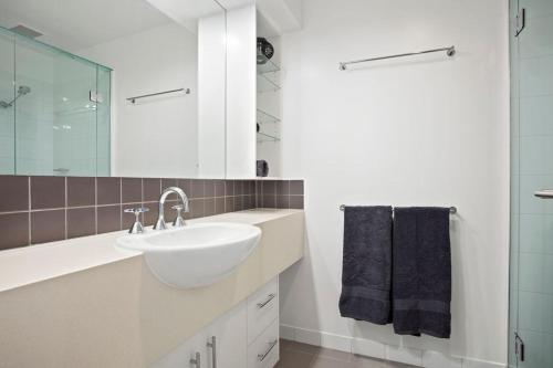Baño blanco con lavabo y espejo en Rip n View, en Point Lonsdale