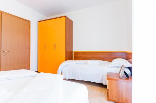 a bedroom with two beds and a cabinet at Pini Village Lido Altanea in Caorle