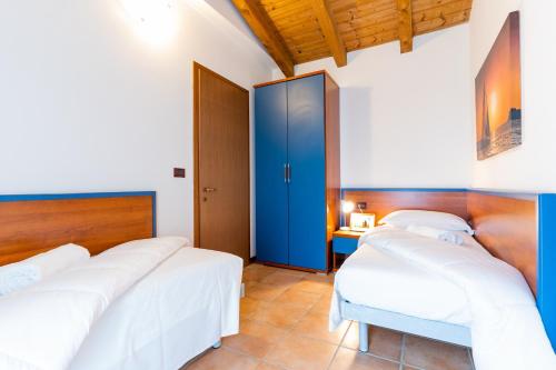 a bedroom with three beds and a blue closet at Pini Village Lido Altanea in Caorle