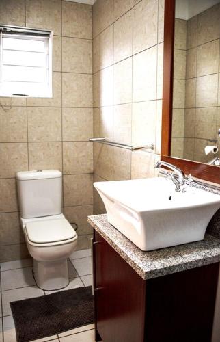 a bathroom with a sink and a toilet and a mirror at Kroon Manor in Kroonstad