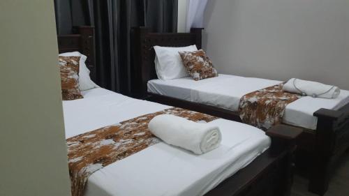 two beds in a room with white sheets and pillows at 1255 Palm Ridge Vipingo Estate Apartments in Kilifi