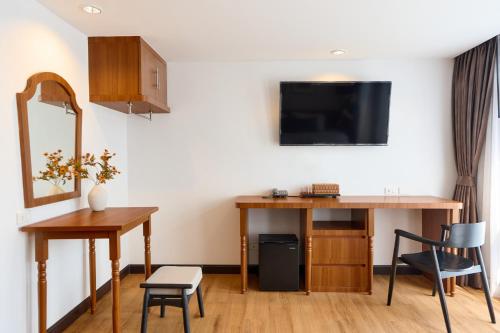 a room with a desk and a tv on a wall at Be Phrasingh Hotel Chiang Mai in Chiang Mai