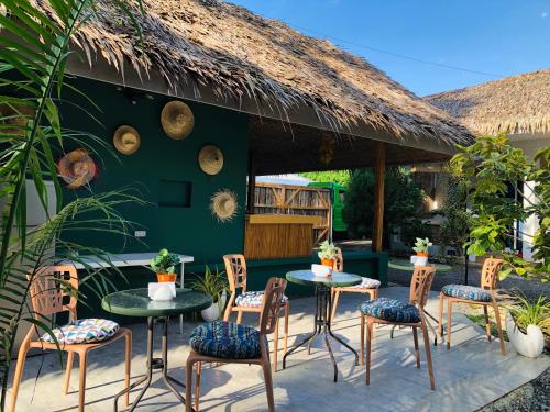 a patio with tables and chairs and a thatch roof at Nautilus Hostel & Hammocks in Panglao Island