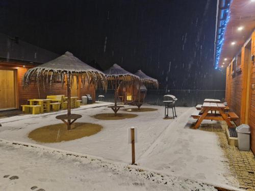 a group of tables and umbrellas in the snow at Apartament z Tężnią Solankową, Sauną, Kominkiem LED i Śniadaniem nad Jeziorem Żywieckim in Zarzecze