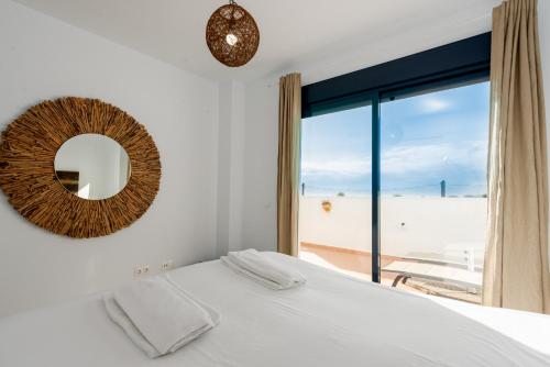 Schlafzimmer mit einem Bett, einem Spiegel und einem Fenster in der Unterkunft Lotus 2401 - Beautiful apartment with pool & sea view in Casares