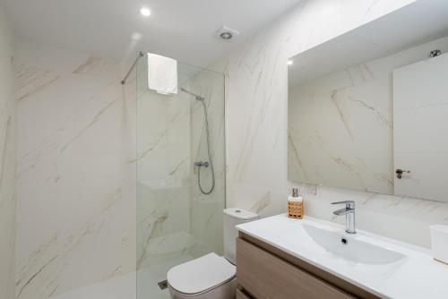 baño blanco con ducha y lavamanos en Lotus 2401 - Beautiful apartment with pool & sea view, en Casares