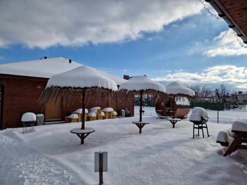 a snow covered yard with chairs and umbrellas at Apartamenty przy Jeziorze Żywieckim z widokiem na Skrzyczne in Żywiec