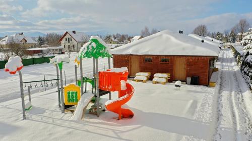 a playground covered in snow next to a building at Apartamenty przy Jeziorze Żywieckim z widokiem na Skrzyczne in Żywiec