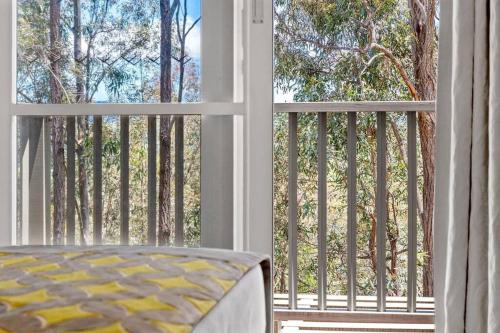 a room with a balcony with a view of trees at King Villa Retreat / Hunter Valley in Pokolbin