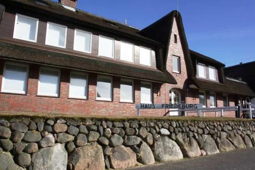 eine Steinmauer vor einem Backsteingebäude in der Unterkunft Haus Friedeburg - Gericke in Rantum