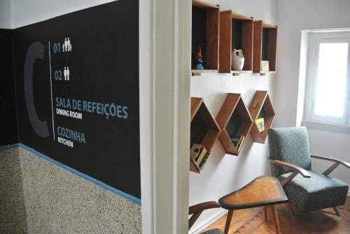a room with a chair and a wall with books at Nazaré Hostel - Rooms & Dorms in Nazaré