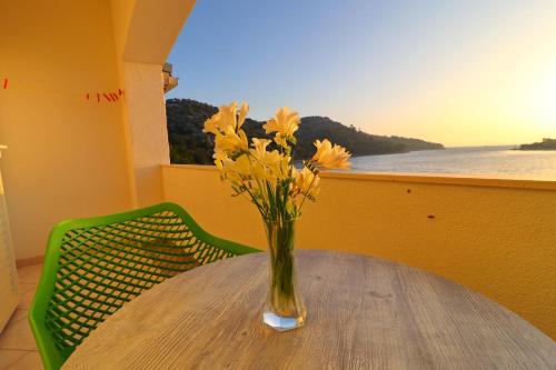 a vase with yellow flowers sitting on a table at Seafront Apartments Anthony in Lastovo