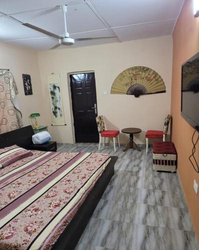 a room with two beds and two chairs and a tv at Eko Akete Guest House in Abeokuta
