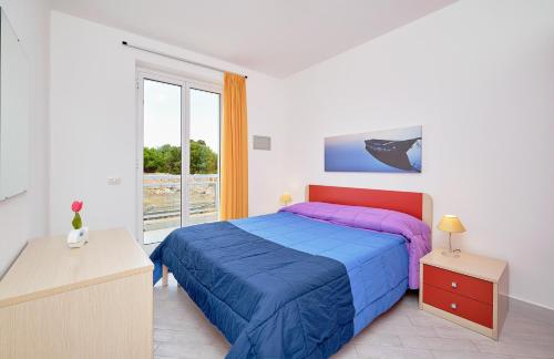 Un dormitorio con una cama azul y púrpura y una ventana en Case Vacanze Pomelia, en Marina di Ragusa