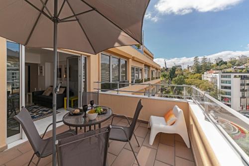 a balcony with a table and chairs and an umbrella at Arriaga I by An Island Apart in Funchal
